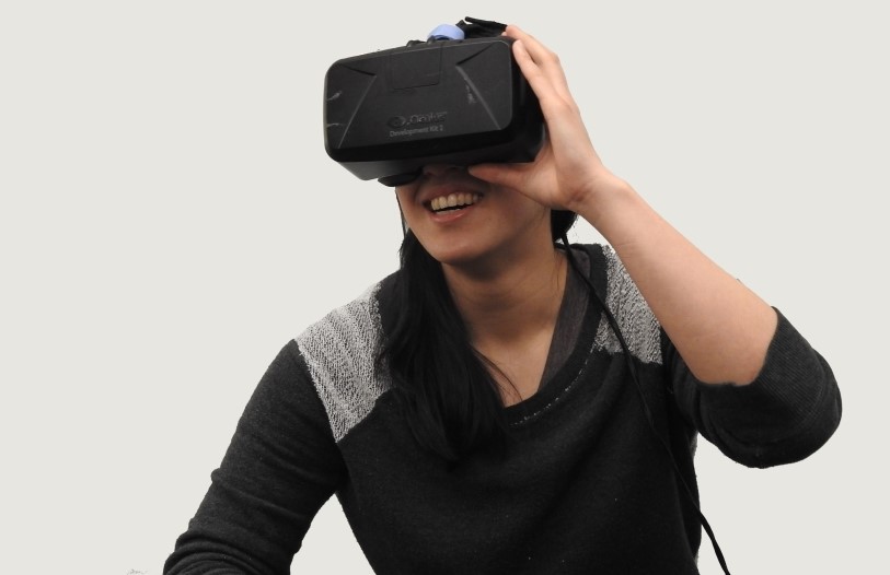 A woman experiencing virtual reality, smiling.