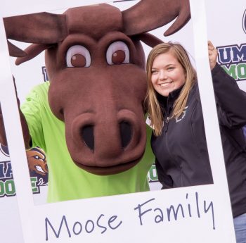 Augustus the Moose poses with a UMA student for a photo