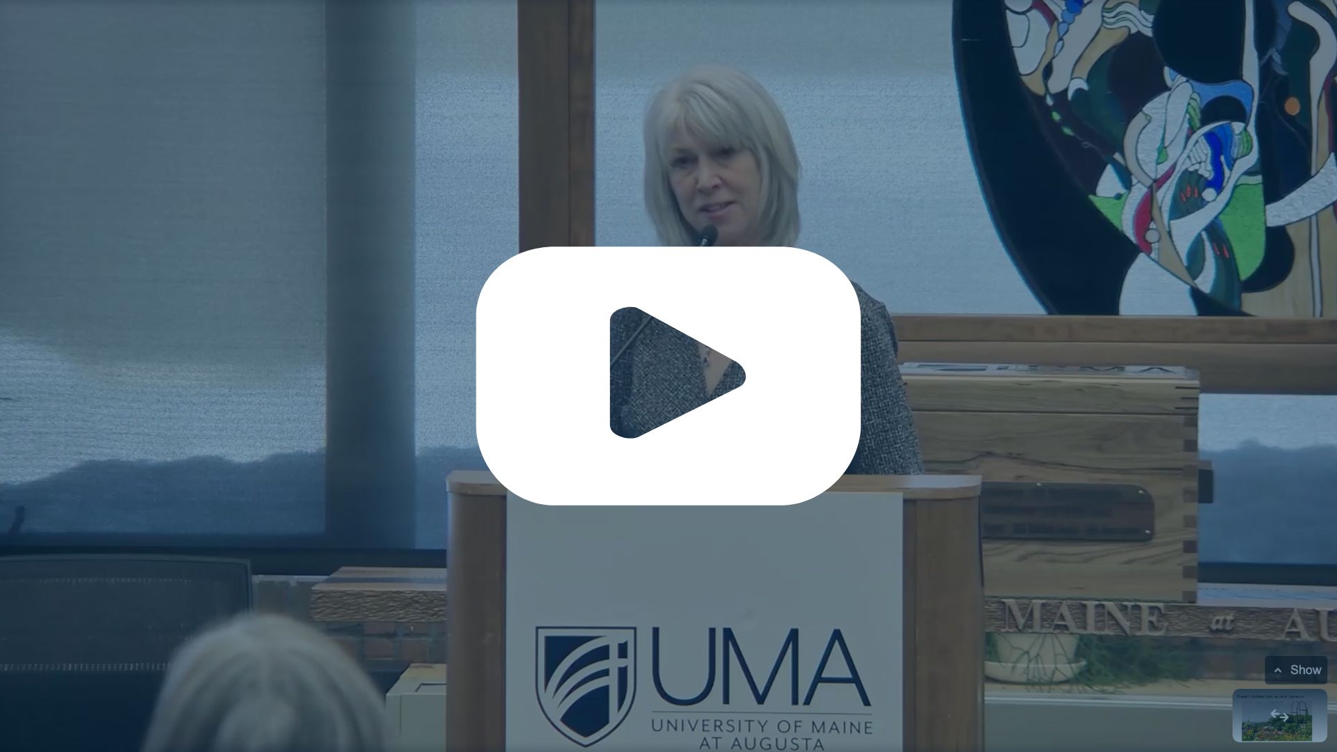 Frame from the Lunch and Learn Live stream with an overlay of a "Play" button