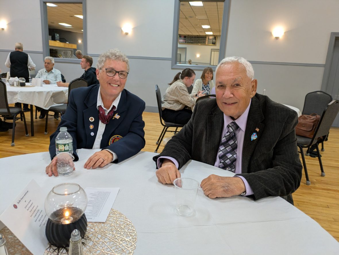 Two attendees seated at a banquet table, smiling for the camera.
