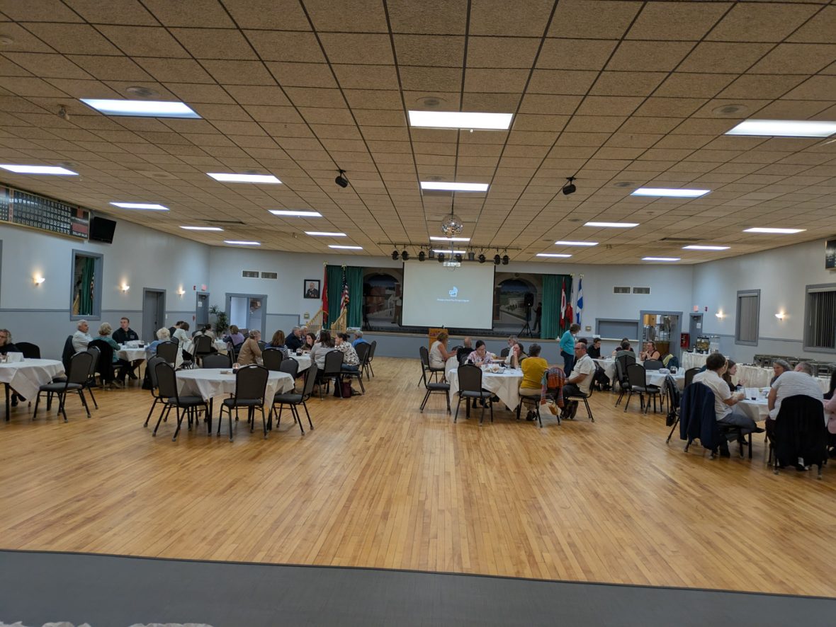 Wide view of attendees seated at tables in a banquet hall during a French immersion event.