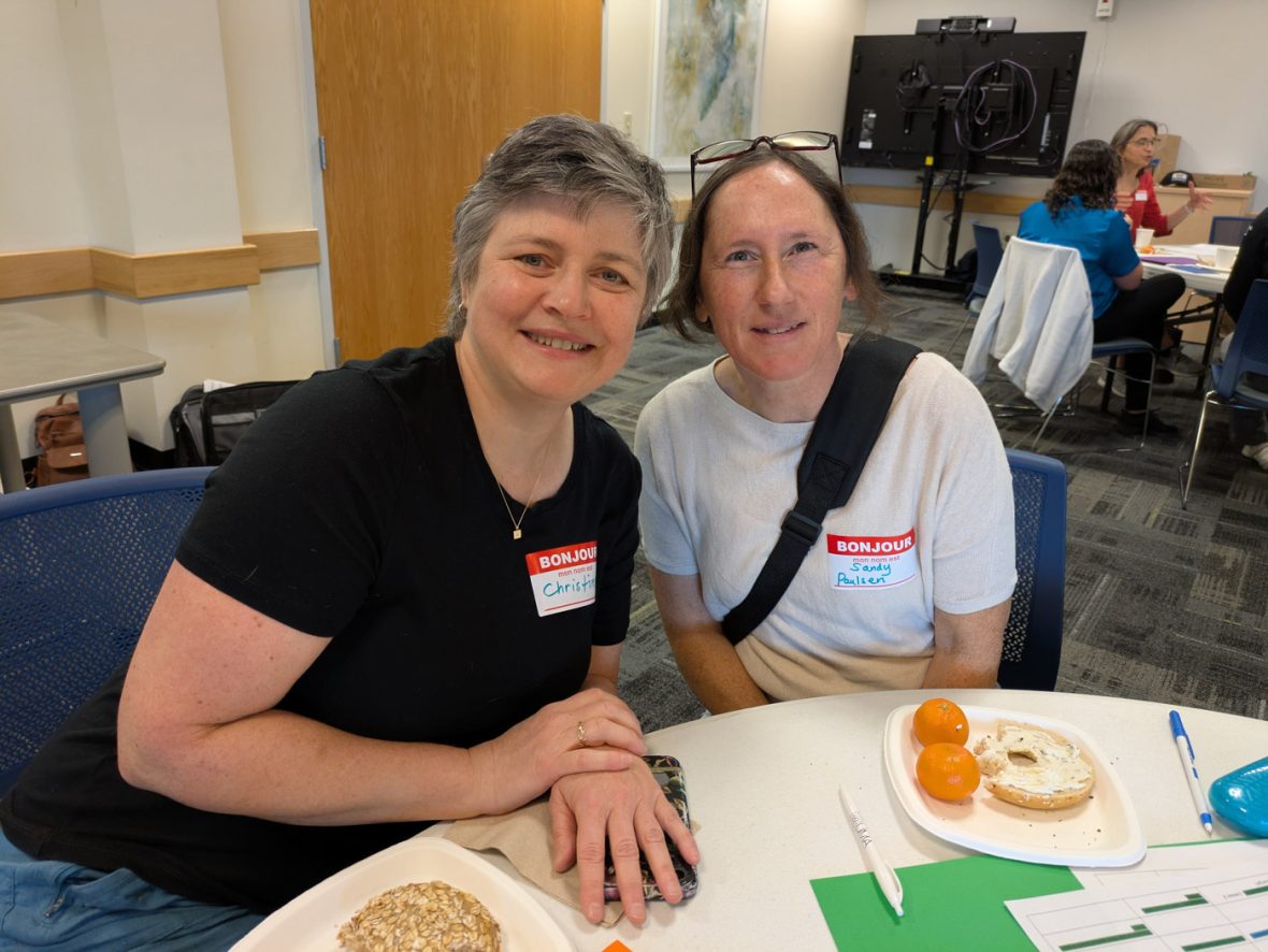 Two participants wearing name tags smile together during a French immersion program.