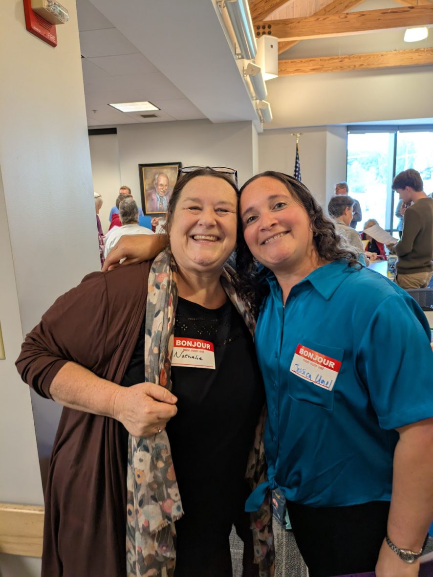 Two participants wearing name tags smile together during a French immersion program.