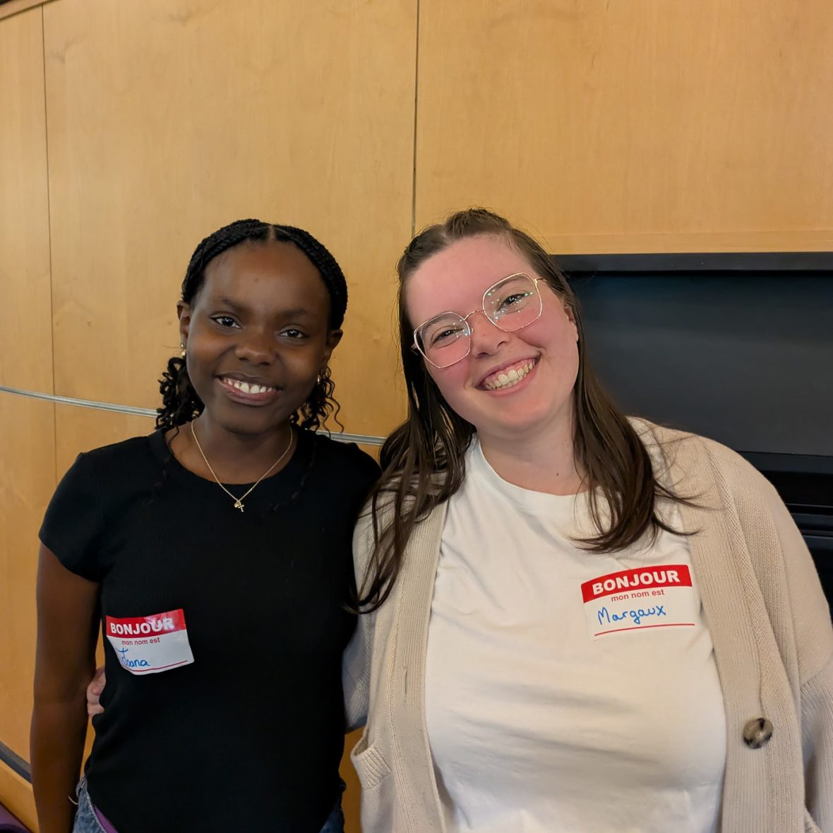 Two participants wearing name tags smile together during a French immersion program.