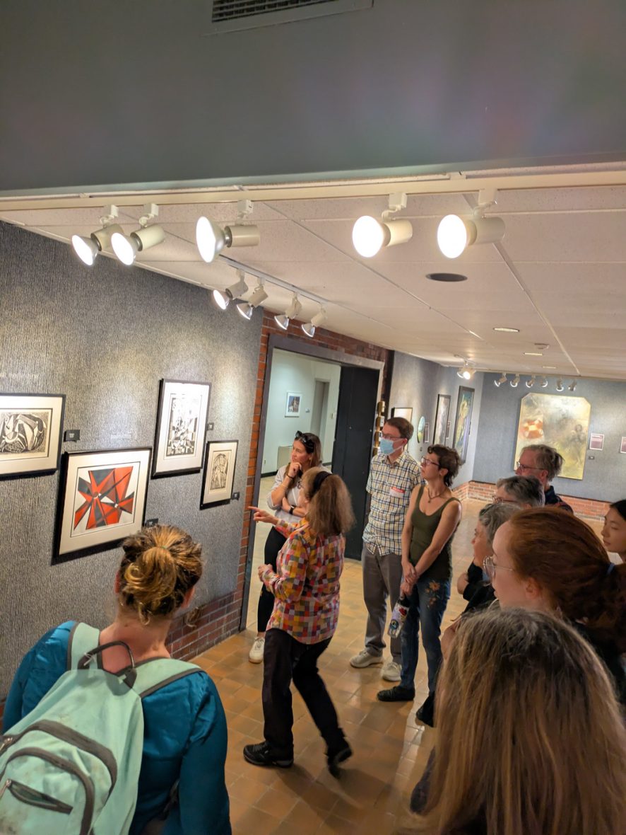 Group tours an art gallery while viewing and discussing artwork on display.