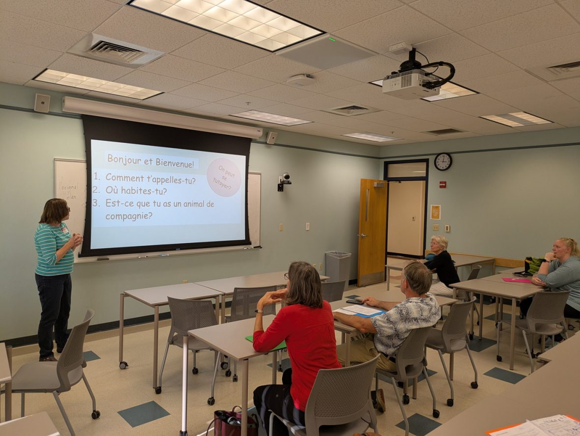 Instructor presents introductory French questions to participants in a classroom.