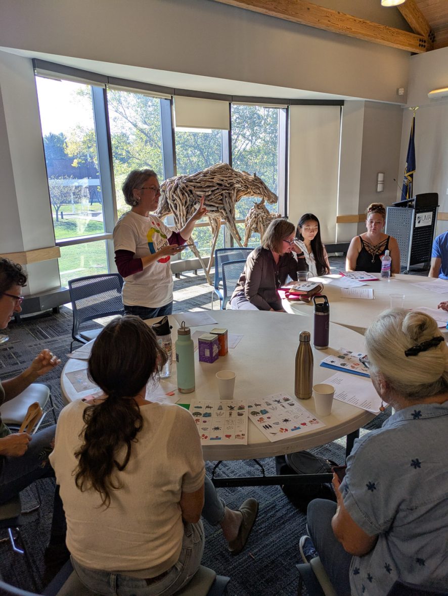 Instructor leads a small-group French immersion activity around a table.