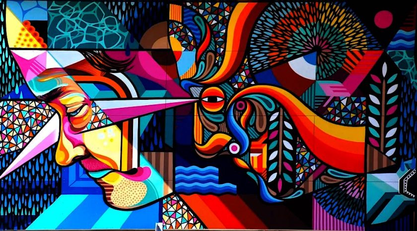 A mural depicting two abstracted faces in colorful shapes, gazing in the same direction toward the left of the frame.