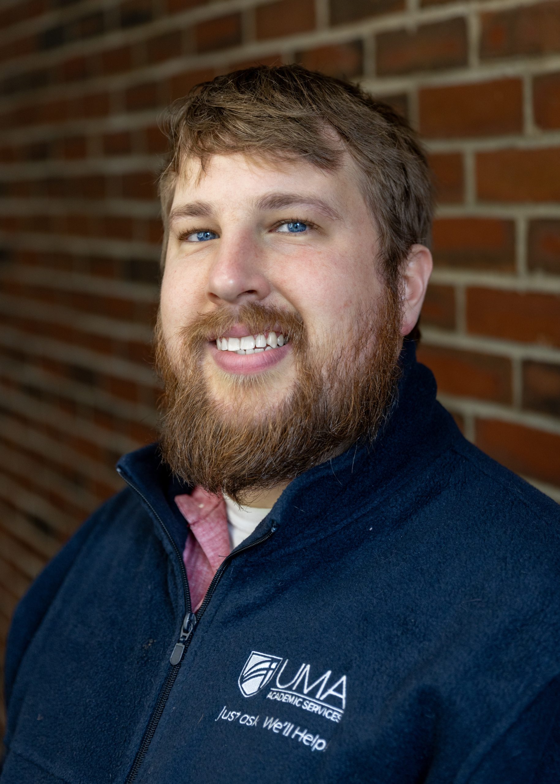headshot of edward hess, wearing a dark blue uma branded fleece sweater.