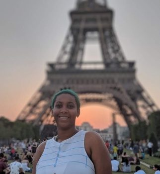 UMA student Destiny, smiling in front of the Eiffel Tower