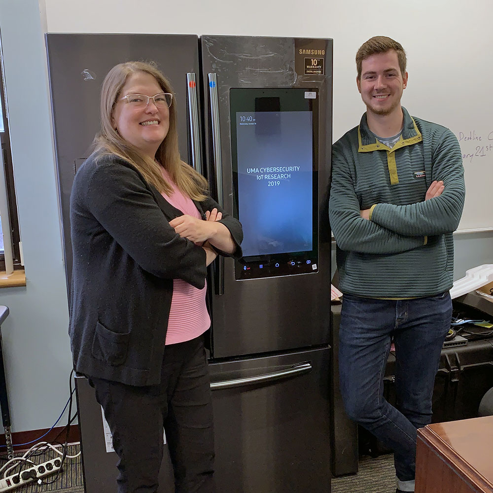 Dr. Betina Tagle on the left and Pierre Laot on the right posing next to the smart fridge associated with the IoT grant
