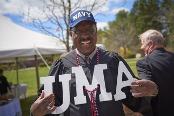 A U.S. Navy Veteran holdin up white letters that spell "UMA"