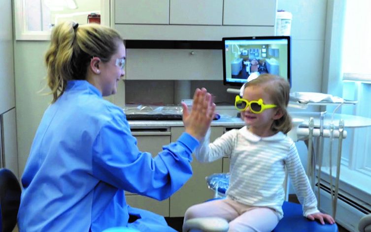 A child giving a high five to a dental student at the Give Kids A Smile Day event.