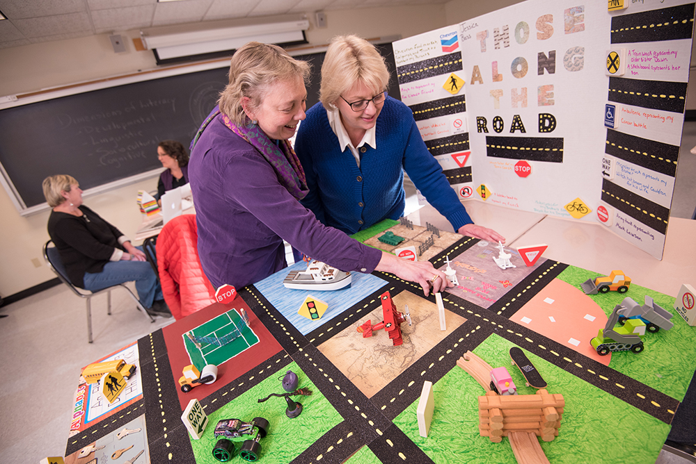 Two UMA professors engaging with educational display