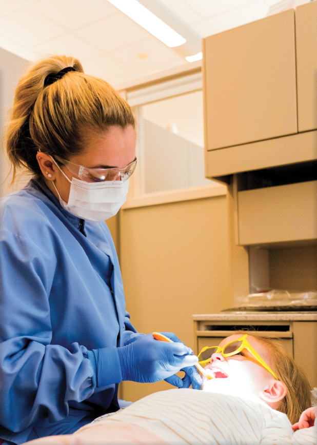 UMA Dental Assisting student cleans the teeth of a child. Photo taken pre-COVID-19.