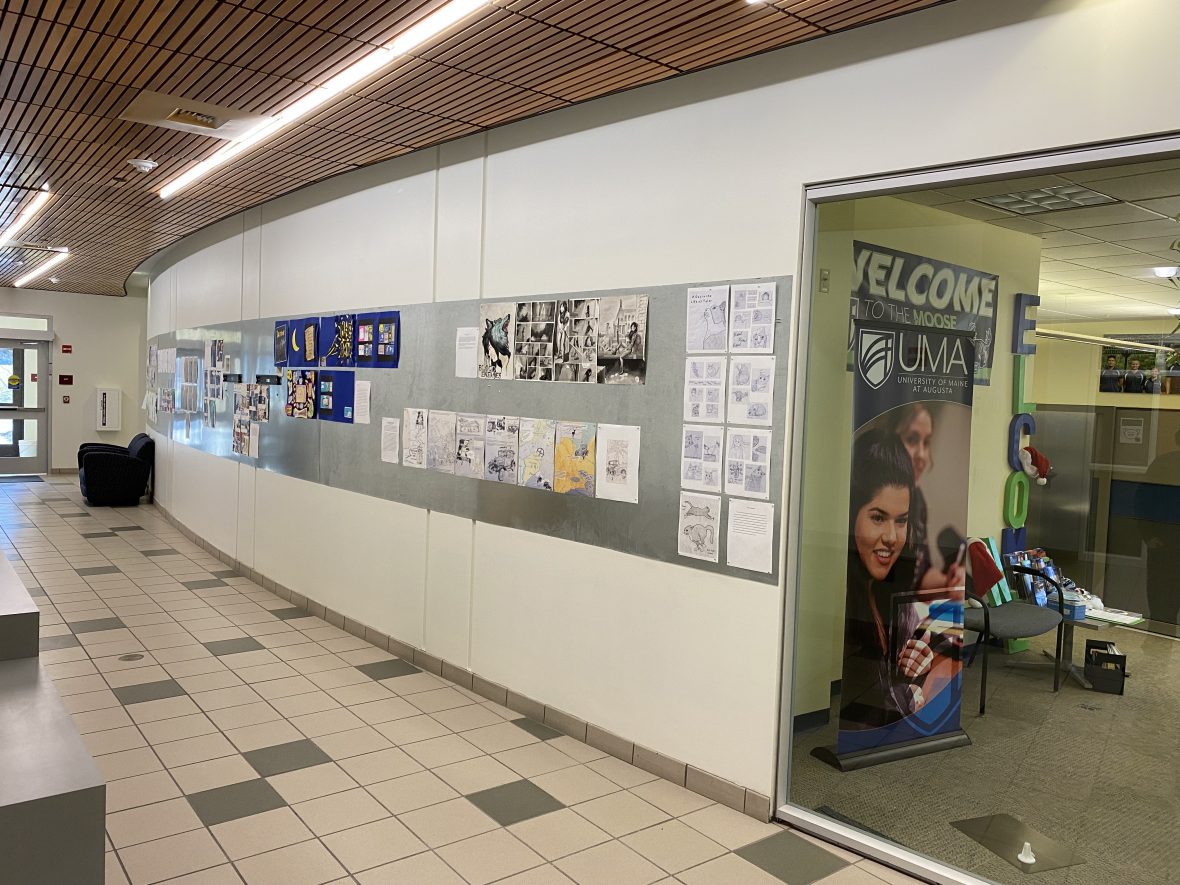 The hallway next to the Admissions office, near Advising, has a display wall covered in student art.