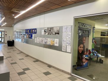 The hallway next to the Admissions office, near Advising, has a display wall covered in student art.
