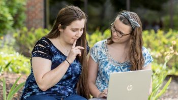two UMA students study outdoors