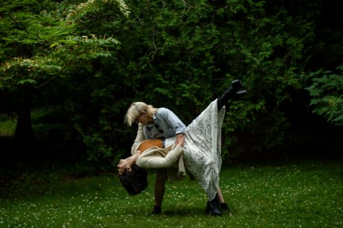a couple dancing outdoors. One is being dipped by the other