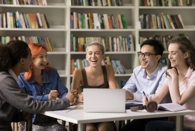 multiethnic team of happy fresh students cooperating on class project