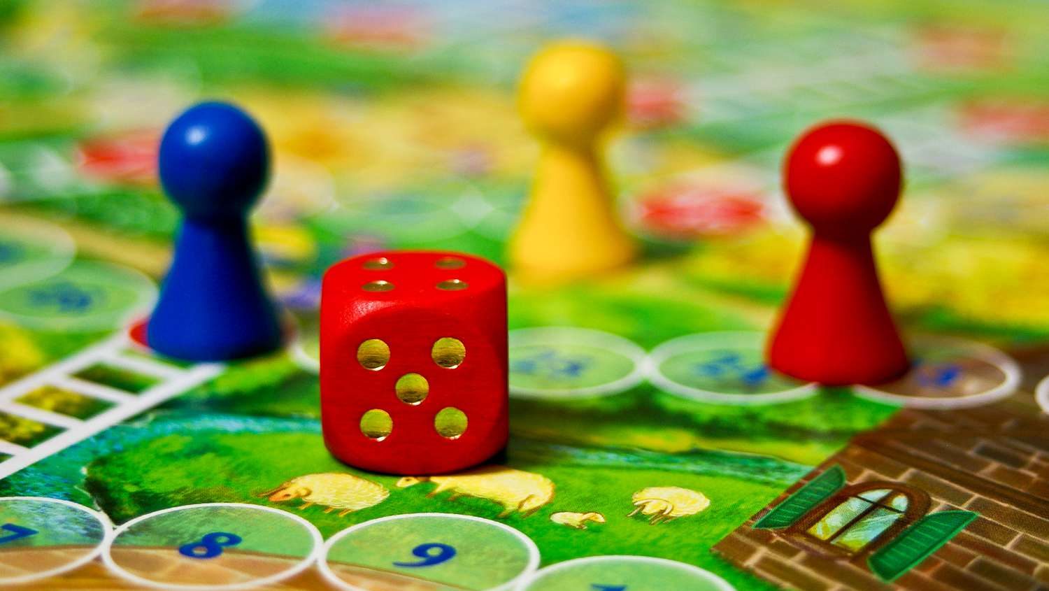 Colorful board game with red die and blue, yellow, and red pawns on a numbered board.