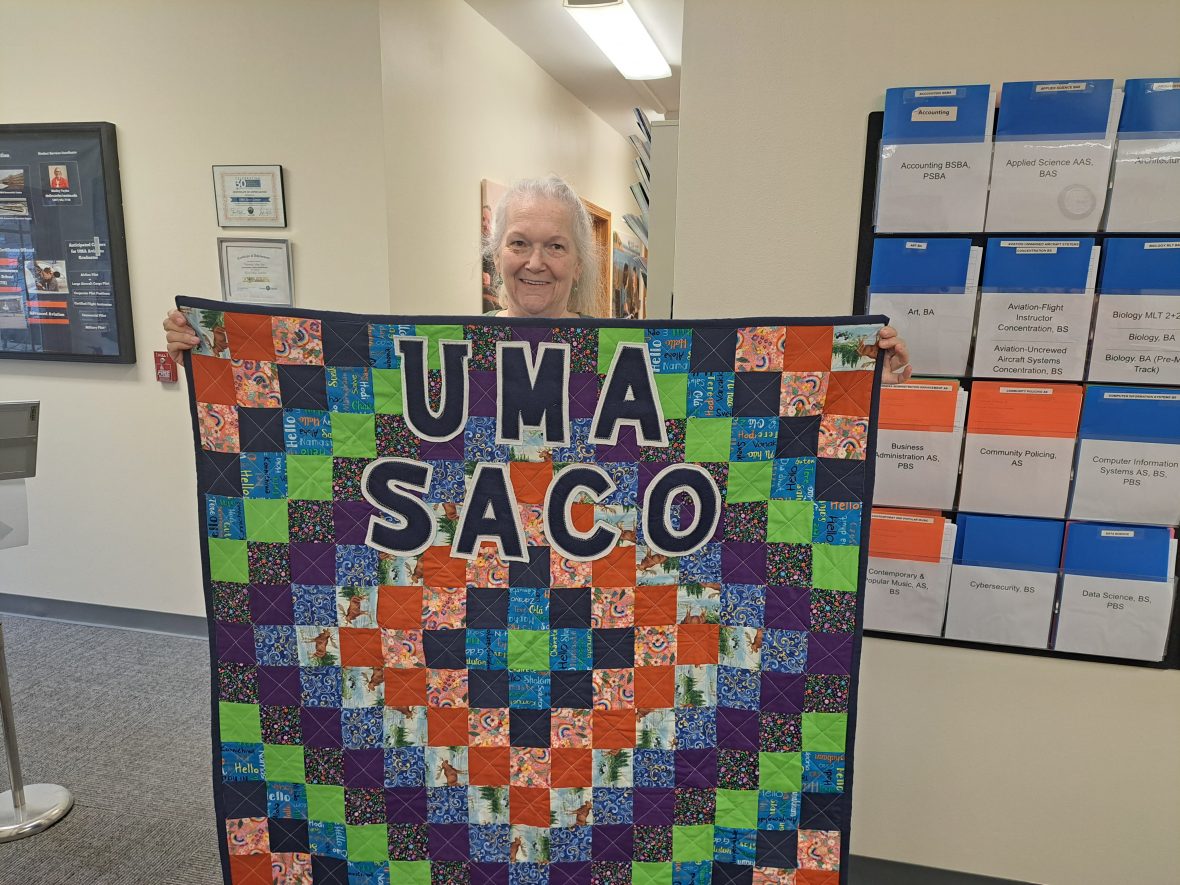 Brenda Plummer, Administrative Assistant at UMA Saco with the quilt she made for the Center.
