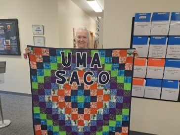 Brenda Plummer, Administrative Assistant at UMA Saco with the quilt she made for the Center.