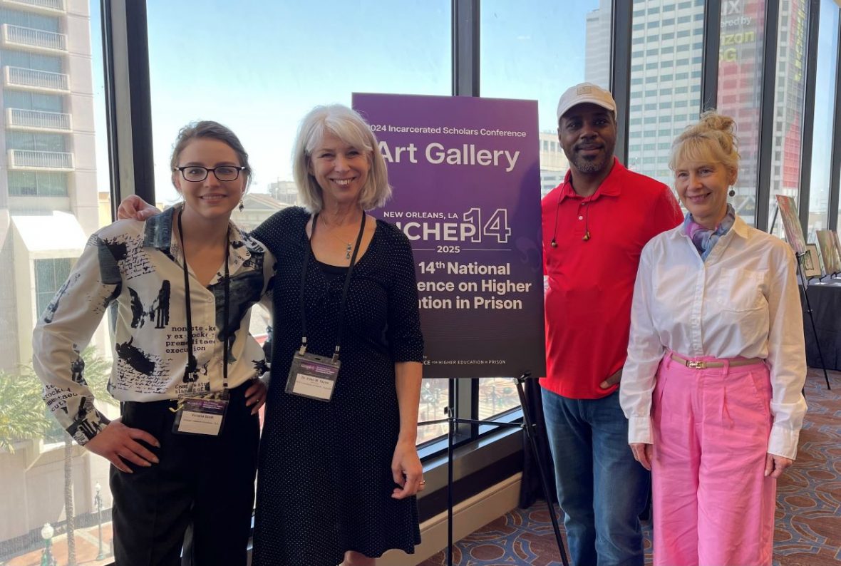 Professor Ellen Taylor with three students/alumni posing by a conference sign