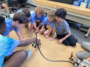 A group of LEGO Robotics campers using their robots on a track built to work with sensors.