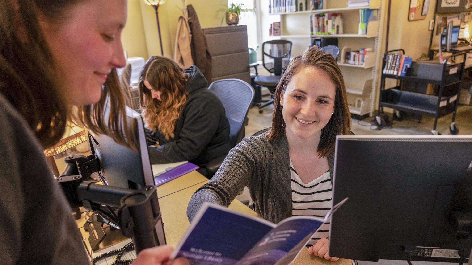 UMA student working at the library circulation desk in Bangor