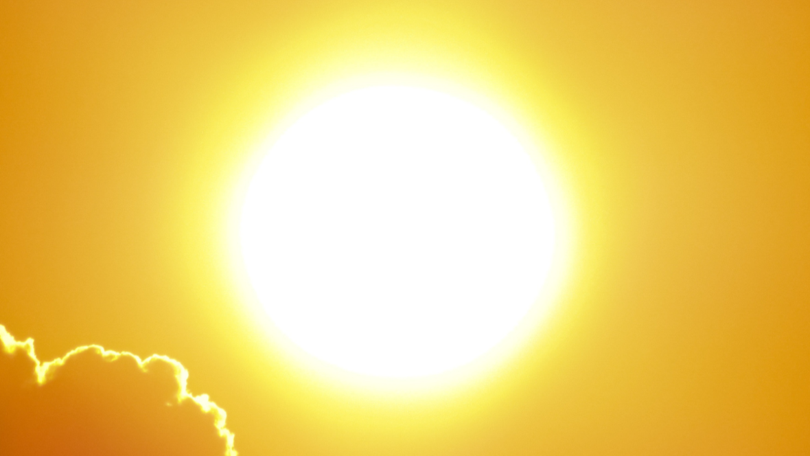 Bright sun glowing in a golden sky with clouds