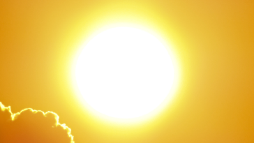 Bright sun glowing in a golden sky with clouds