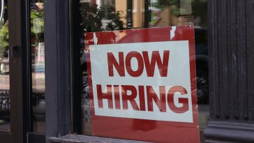 "Now Hiring" sign in a window