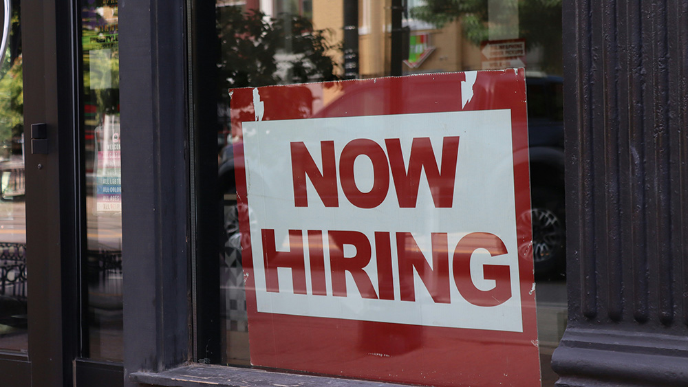 "Now Hiring" sign in a window