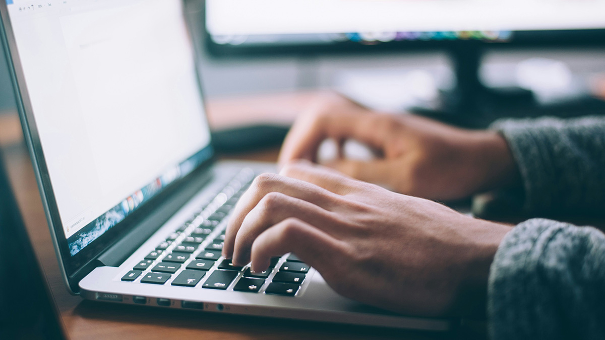 close up of hands typing on a laptop keyboard
