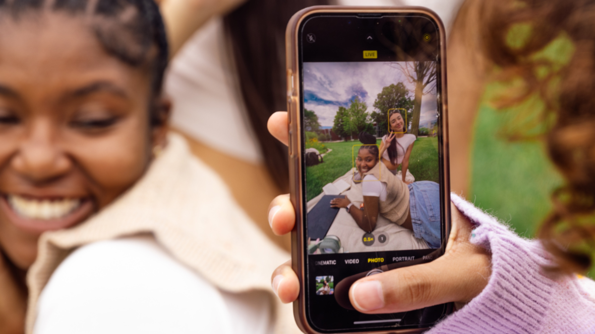 A phone captures three young women smiling and posing