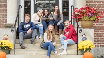 UMA students sitting on the front steps of Stevens Commons residence hall