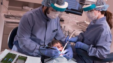Two dental assisting students practicing with a patient