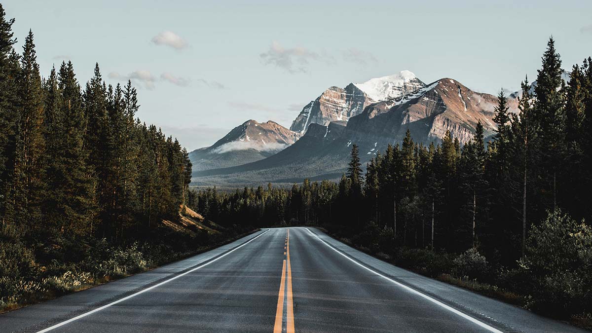a paved road leading to mountainous landscape