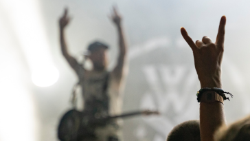 A person doing a rock on sign with their hand at a concert