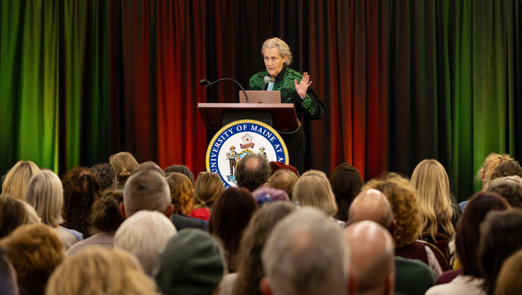 Temple Grandin at a podium speaking to a sold out crowd at the Augusta Civic Center as part of her visit to UMA