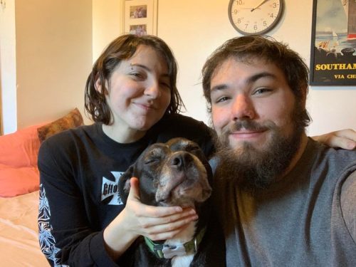 a woman and a man sitting together with a dog between them