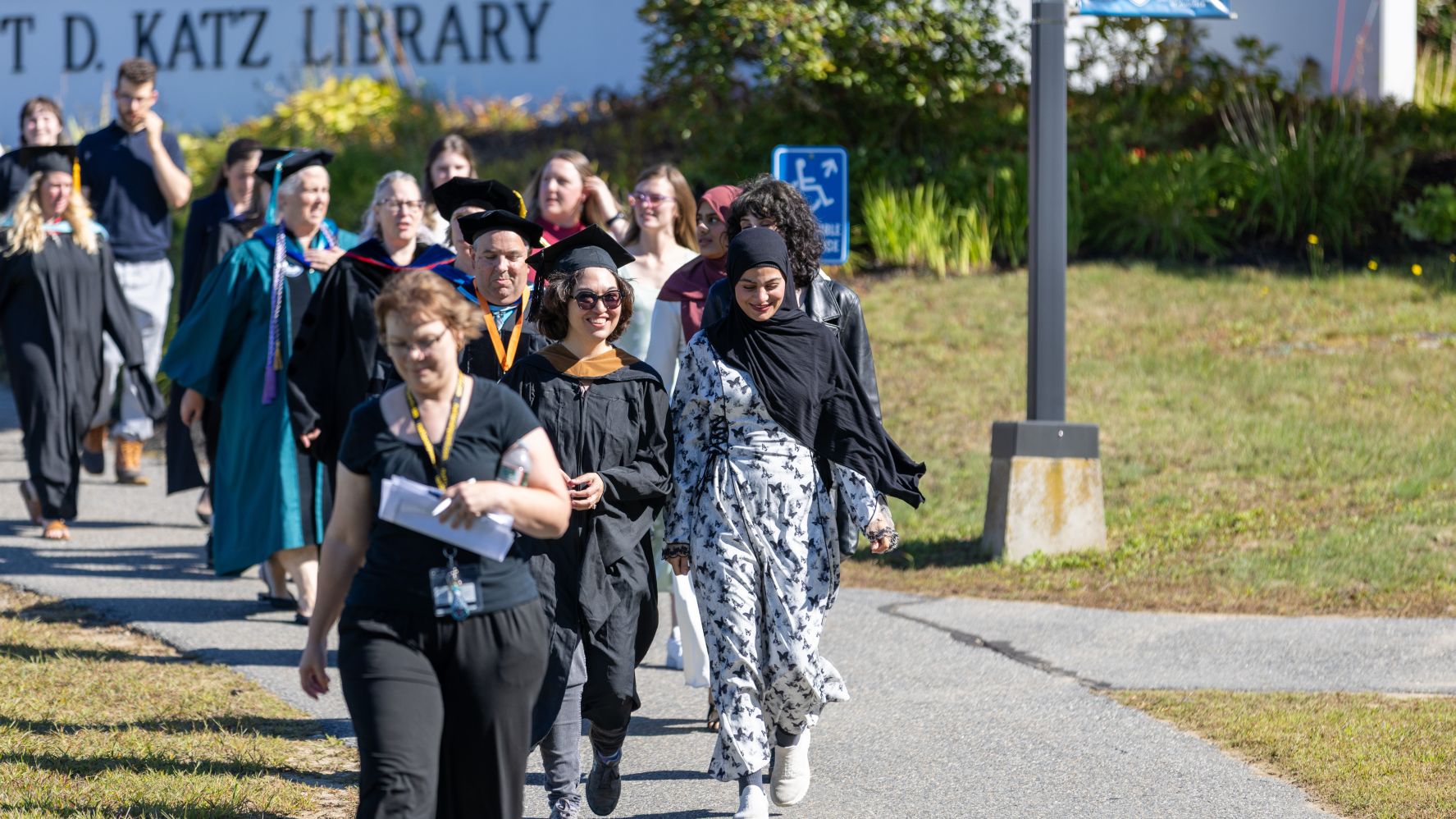 Rising scholars and professors in academic regalia walk together toward the convocation ceremony.