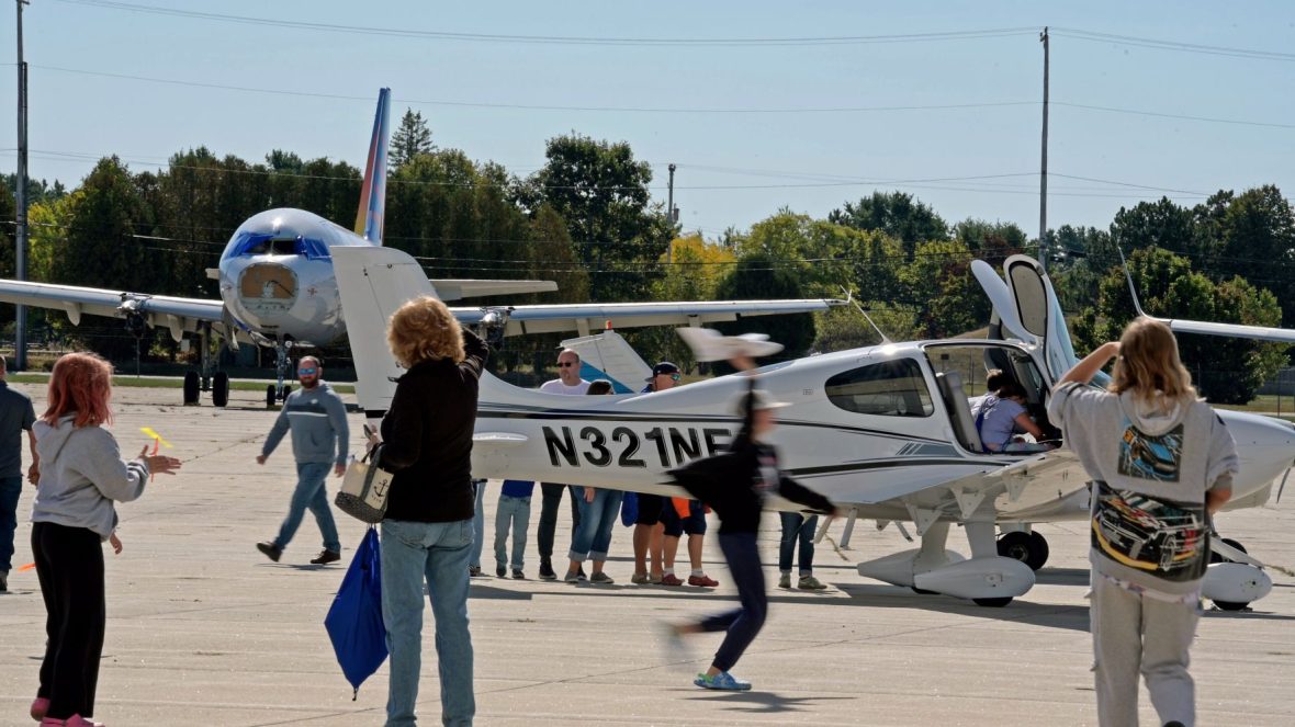 Children of all ages sit in plane cockpits, fly drones, and rivet.