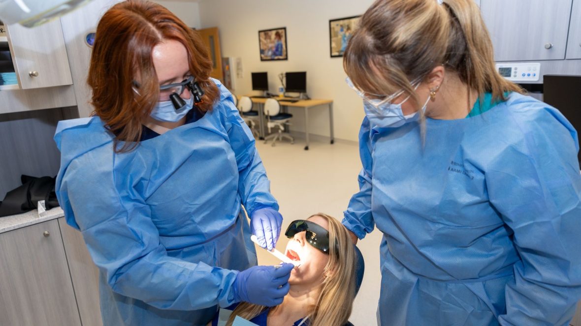 Dental professor watches as student practices skills