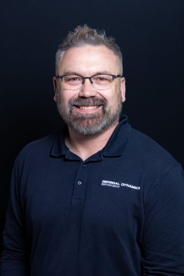 UMA alumnus Rion Turner '20 wears a navy blue shirt from General Dynamics Bath Iron Works