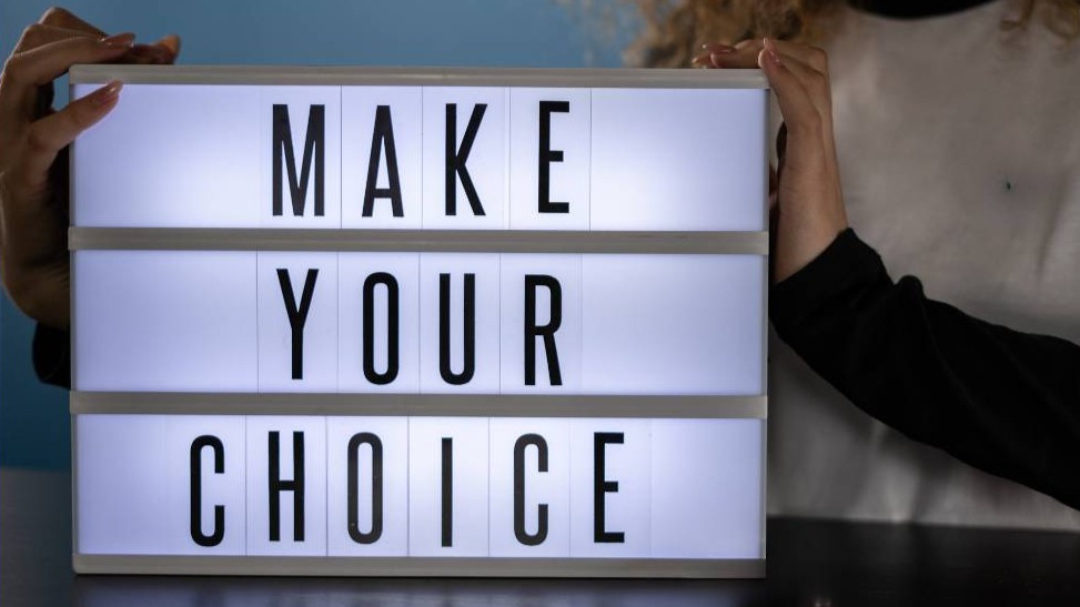 A woman holding a light up sign saying "Make Your Choice"