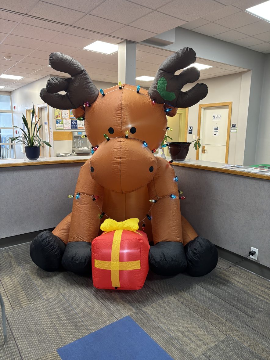 inflatable moose wrapped in holiday lights holding a present