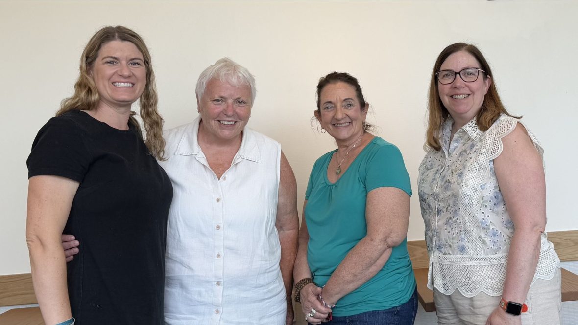 Four faculty leaders from UMA and UMF stand together smiling. From left to right: Dr. Nicole Achey, Dr. Kim Lane, Dr. Karen Barrett and Dr. Wendy St. Pierre. They are pictured indoors, close together, reflecting the partnership behind the behavioral health workforce initiative.