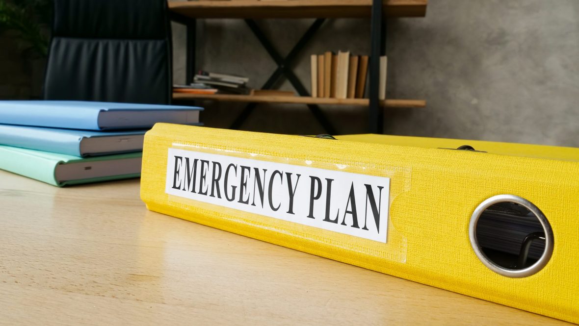 Yellow folder labelled "emergency" on a desk.